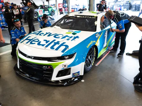 AdventHealth racing car in garage with pit crew surrounding it 