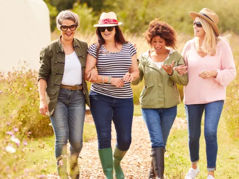 A Group of Inspiring Women Walk Through a Garden Smiling and Laughing