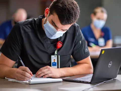 An AdventHealth nurse writing in his notepad
