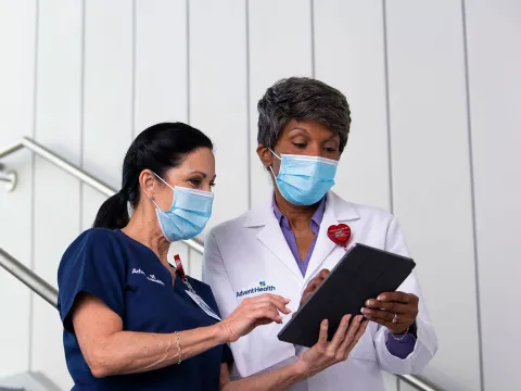 A AdventHealth nurse and physician in a discussion while holding a tablet.