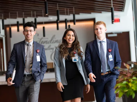 Three young professionals walking in the hallway of an office building