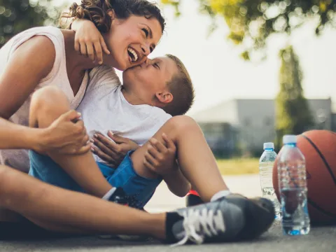 A mother and son take a water break on the basketball court during the summer.