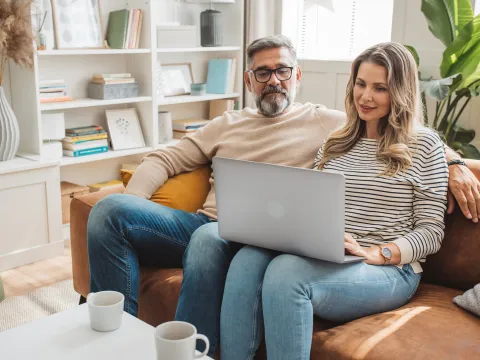 Couple looking at laptop togeter on couch.