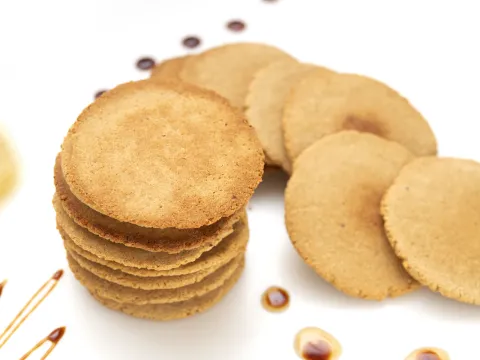 16 round, flat, golden cookies on a white surface