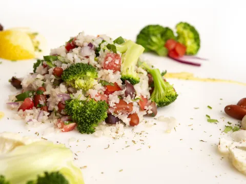 Mound of cauliflower rice salad with lemon and broccoli garnishes