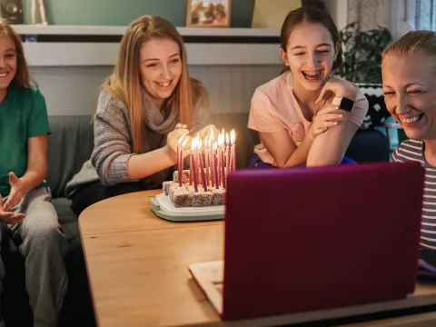 A family celebrating a birthday over video chat. 