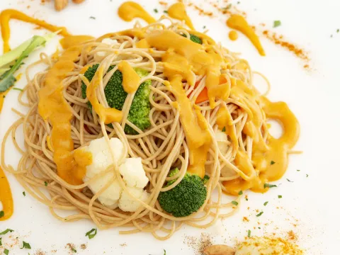 Mound of cheesy vegetable pasta on white surface