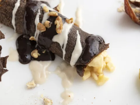 Chocolate crepe with banana filling on white surface