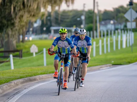 Triathlon participant, Chris Nikic, and his physical therapist, Trevor Hicks, biking on the road