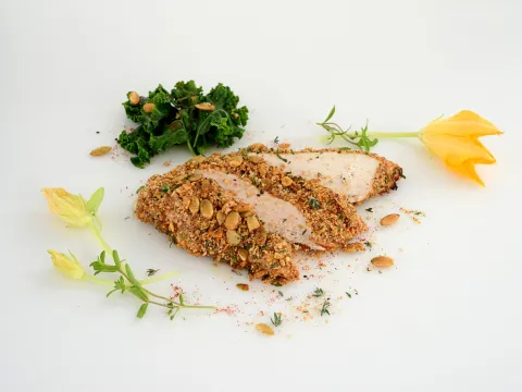 a serving of chicken, coated in a pumpkin seed crisp, sliced into three pieces