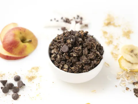 Bowl of chocolate granola with apple garnish on the side