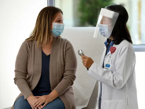 A doctor examines a patient wearing personal protective equipment.