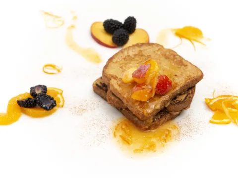 three stacked slices of french toast, topped with a fruit sauce 