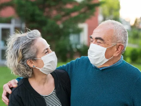 older couple wearing masks outdoors.