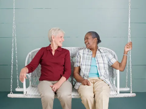 Two older women sitting on a porch swing.