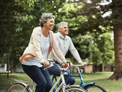 Older couple riding bikes outdoors together,