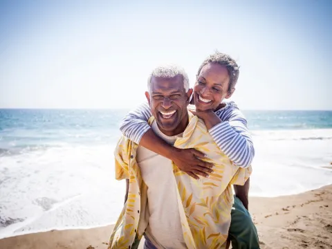 An older couple smiling while at the beach.