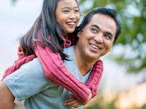 A father giving his young daughter a piggyback ride