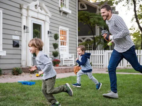 A father playing softball with his youngsters in the patio.
