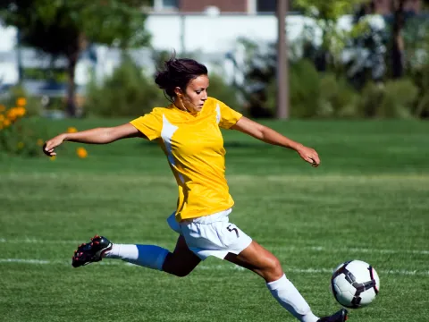 A female soccer playing kicking a soccer ball