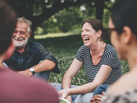 people sit in a circle on a beautiful day in the park