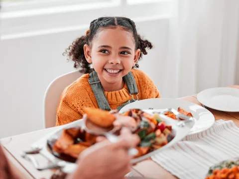 A girl smiling at the dinner table.