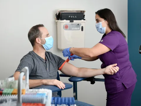 Lab technician preparing man for a blood draw.