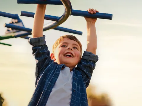 A little boy playing on the monkey bars