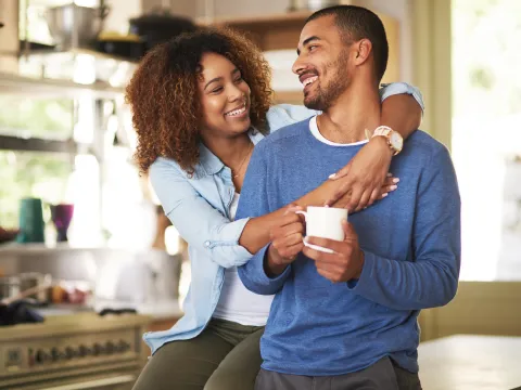 A couple hugs in their kitchen at home.