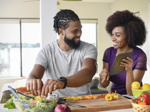 A couple making a salad from a recipe.