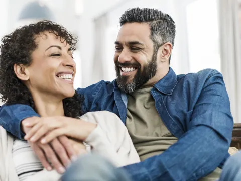 A couple laughs together on the couch.