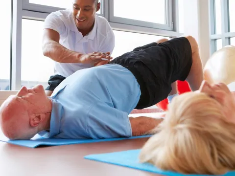 A couple does stretching and strengthening exercises with a physical therapist. 