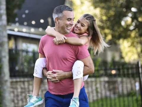 A dad giving his daughter a piggyback ride.