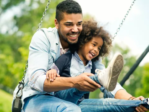 A dad swings with his giggling child.