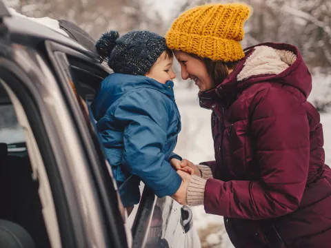 A mom prepares for a road trip with her family in the snow.