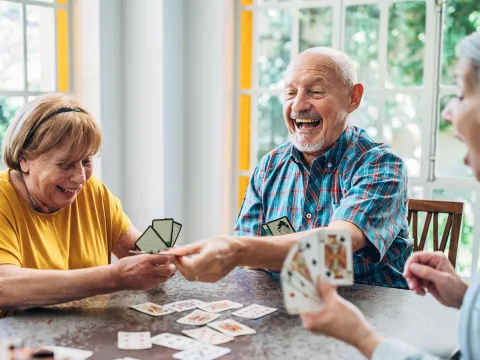 A group of senior adults play cards at home