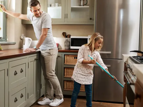 A father and his young daughter clean the kitchen