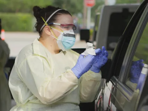 Health Care employee talking to a patient at a drive up testing site