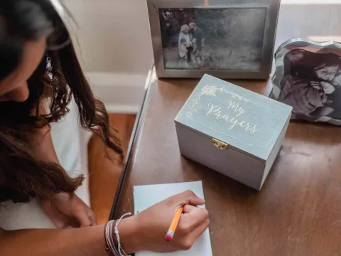 Girl writing prayer with prayer box