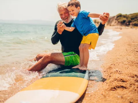 A grandfather teaches his grandson to surf.