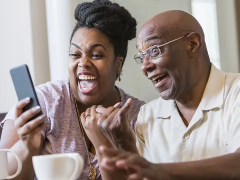 A couple laughing on a video call.