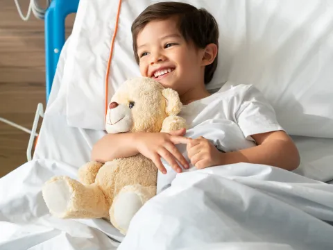 A little boy hugs his teddy bear while in the hospital.