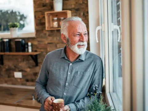 A man enjoying a cup of tea looking out the window.