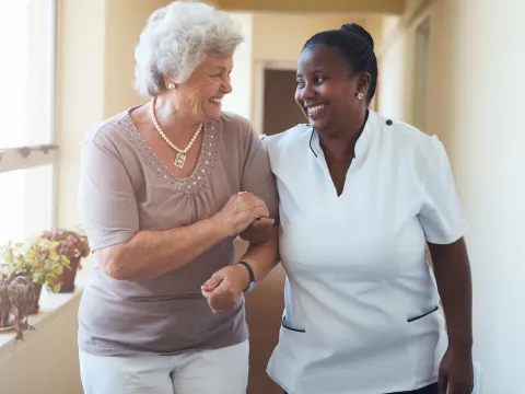 A woman walks with her nurse for treatment during an appointment.