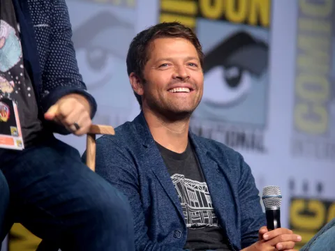 Actor Misha Collins sits onstage at Comic Con with his cast members