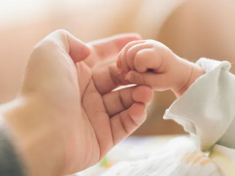 A baby holding one of her mother's fingers