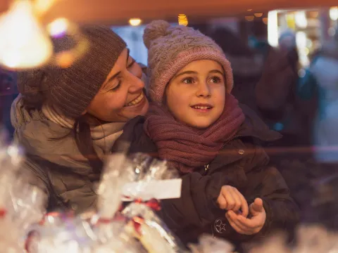 A mother and child looking at holiday storefronts.