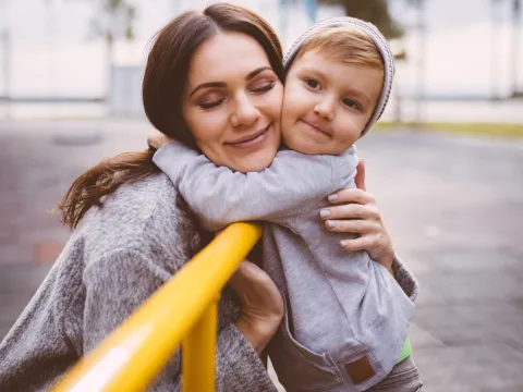 A mom hugs her son at the playground.