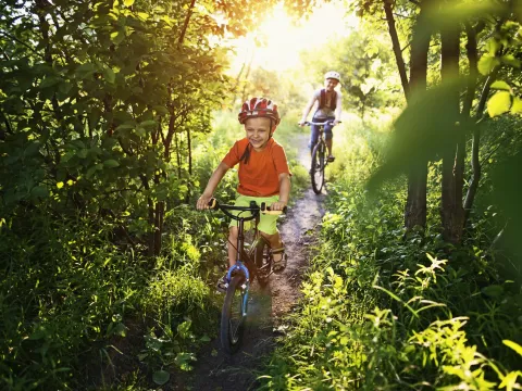 A boy races his bike ahead of his mom on the trail