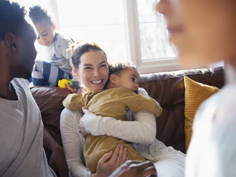 Woman holding child while sitting with family